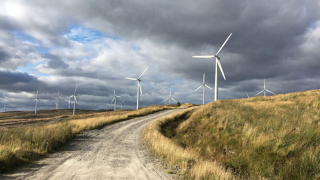 Rosehill Wind Farm against a backdrop of great clouds and yellowing grass